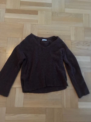 Mörkbrun stickad tröja med V-ringning Stockh LM - Mysig mörkbrun stickad tröja med V-ringad hals och långa ärmar. Stockh LMTröjan har en enkel, avslappnad passform och är perfekt för kyliga dagar. Materialet känns mjukt och behagligt mot huden. Passar till jeans eller kjol för en chill look.