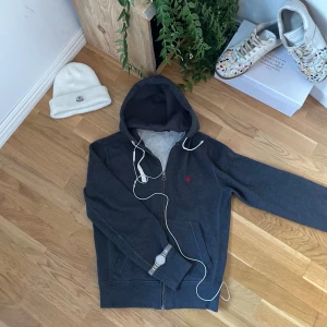 Polo ralph lauren Zip hoodie - Säljer en Fet Ralph lauren zip hoodie som passar perfekt till vintern❄️, eller bara att ha i skolan/hemma🤩🤩. Storlek: smal/medium. Färg: Grå med rött märke. Tveka inte med att ställa frågor och komma med bud!! Fraktar snabbt😍📦📦 Köpt är köpt👈👈