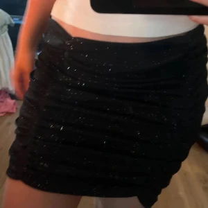 Svart klittrig kjol - Snygg svart kortkjol med glittrande detaljer. Perfekt för en kväll ute eller festliga tillfällen. Kjolen har en tight passform som framhäver figuren. Aldrig använd💕