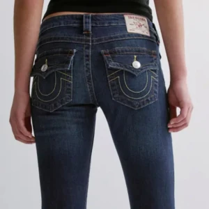 Mörkblå jeans från True Religion - Snygga mörkblå jeans från True Religion med låg midja och raka ben. Jeansen har ikoniska bakfickor med kontrasterande gul och vit söm samt silverfärgade knappar. Klassisk femficksmodell i stretchigt denimtyg som sitter riktigt bra.