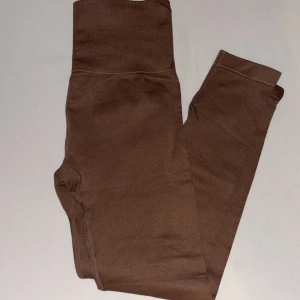 Bruna träning leggings med hög midja, S - Snygga bruna leggings med hög midja och ribbad linning. Tillverkade i mjukt och stretchigt polyamidmaterial med elastan för extra komfort. Perfekta för träning eller chill. Färgen är varm brun och passformen är tight.
