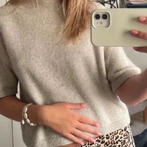 & other stories - Supermjuk beige stickad tröja med korta ärmar och rund hals. Perfekt för lager-på-lager och enkel att styla till både jeans och kjol. Tröjan har en klassisk passform och ribbad kant vid halsen.