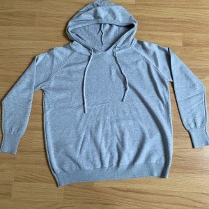 Ljusgrå hoodie med huva och snörning - En stilren ljusgrå hoodie med huva och snörning. Tröjan har långa ärmar, ribbade muddar och nederkant. Perfekt för en chill och avslappnad look. Materialet känns mjukt och skönt mot huden.🤩 ALDRIG använt för köpte fel storlek den passa dom som e 150 tror jag eller 160!!! Hör av er för fler frågor!!!