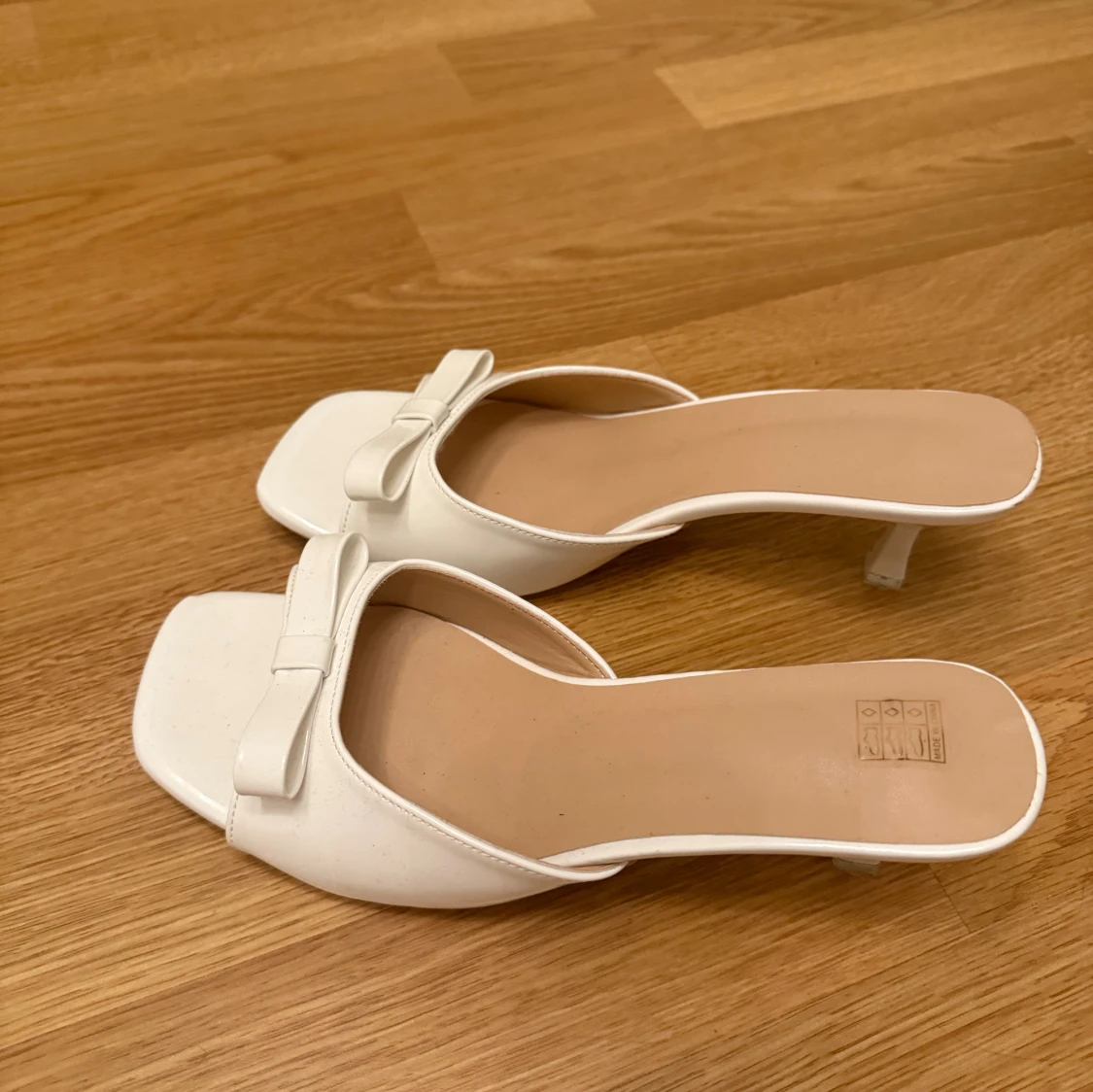 Vita klackar med rosett och låg klack