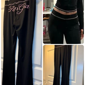 Svarta bootcut byxor från S - Snygga svarta bootcut byxor från  med rosa sömmar och stor rosa logga på baksidan. Byxorna har hög midja och är gjorda i ett stretchigt syntetmaterial som sitter tajt över höfterna och låren. Perfekta för dig som gillar statement-plagg.