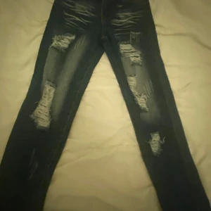 Mörkblå ripped skinny jeans - Snygga mörkblå jeans med slitna detaljer och flera revor framtill. Modellen är skinny med normal passform och klassiska bakfickor. Perfekt för dig som gillar en edgy streetstil. Materialet är jeans och färgen är mörkblå med ljusare slitningar.
