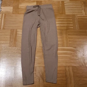 Beige ribbade leggings med snörning XS - Snygga beige leggings i ribbad bomullsmix med hög midja och snörning framtill. Modellen är slim och sitter tight längs benen, perfekt för chill eller att styla med oversized hoodie. Storlek XS (EU 34).