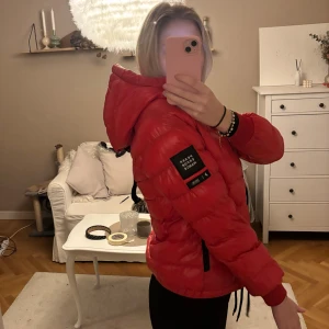 Peak performance jacka - Säljer min röda dunjacka från peak med huva och svarta detaljer. Jackan har en snygg quiltad look, dragkedja framtill och två fickor med dragkedja. Perfekt för dig som vill ha en varm och lätt jacka med cool streetstil.
