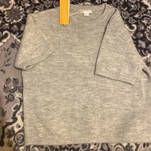 Grå stickad tröja från Gina Tricot - Mysig grå stickad tröja från Gina Tricot i storlek 158/164. Tröjan har korta ärmar och rund halsringning, perfekt för lager-på-lager. Enkel och stilren design som funkar till allt. Supermjuk och skön att ha på sig.