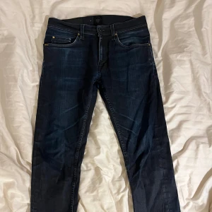Mörkblå jeans Tiger of Sweden 29/34 - Snygga mörkblå jeans från Tiger of Sweden, modell Pistolero. Klassisk femficksdesign med raka ben och normal passform. Jeansen är tillverkade i slitstarkt denim och har stilrena detaljer med svarta och guldfärgade nitar. Använt fåtal gånger. 