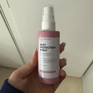 By Veira Heat Protection Spray - Snygg värmeskyddsspray från By Veira i en rosa och vit plastflaska med pump. Sprayen är vegansk och bevarar färgen samtidigt som den skyddar håret mot värme, ger glans och återfuktar. Knappt använd.