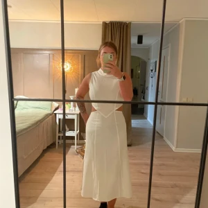 Vit långklänning med slits och cut-outs - Säljer en vit långklänning från Avora. Stilren och modern design. 