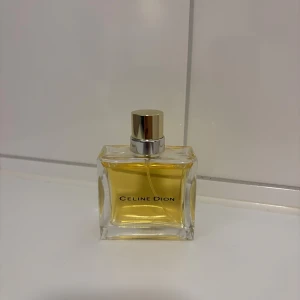 Celine Dion parfymflaska - Stilren parfym från Celine Dion i en transparent flaska med guldfärgad vätska och guldlock. Perfekt för dig som vill ha en ikonisk doft på hyllan. Bara använd 2 ggr. 