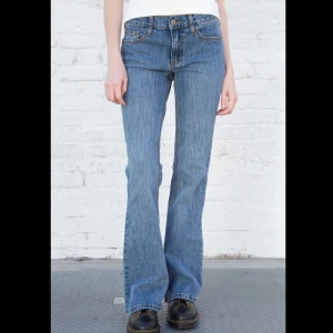 Brandy Melville jeans - Brandy Melville ”Brielle 90s jeans” jeans i blå tvätt med bootcut passform. Jeansen har fem fickor, knapp och dragkedja framtill samt subtila sömmar. Perfekt för dig som gillar retrovibbar och vill ha ett par jeans med lite utsvängda ben.