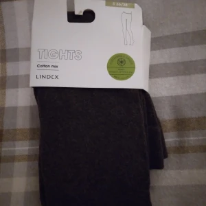 HELT NYA OANVÄNDA bruna tights / strumpbyxor från Lindex, S 36/38 - Tjocka och mjuka bruna/mörkbruna tights/strumpbyxor från Lindex i storlek S 36/38, men Passar troligen även någon med XS-S. Tillverkade i en skön bomullsblandning med ekologisk bomull, polyamid och elastan. Perfekta att bära under kjol eller klänning när du vill ha extra värme och komfort. Passar extra fint på hösten. Felfria.
