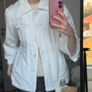 Vit peacoat med stora knappar - Snygg vit jacka/peacoat med oversized krage och stora dekorativa knappar framtill. Jackan har trekvartsärmar och markerad midja för en clean och stilren look. Perfekt för dig som vill sticka ut med detaljer🫶🏻