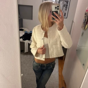 Vit croppad kavaj med knappar - Säljer en vit croppad kavaj med rund hals och snygga silvriga knappar framtill. 