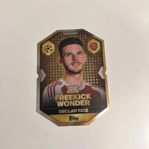 Freekick Wonder - Unik samlarkort från Topps med Declan Rice, Arsenal-mittfältare och Chrome Award Winner. Kortet hyllar hans mästerliga frisparkar i Champions League mot Real Madrid. Perfekt för unga fotbollsfans och samlare som vill ha något extra i sin kollektion.