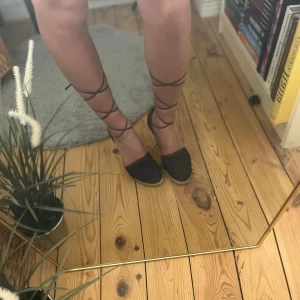 Bruna kilklackade espadriller med snörning - Snygga bruna espadriller med kilklack och snörning som går upp längs vaden. Ovandelen är i virkad textil och klacken är täckt med flätad jute för en somrig vibe. Perfekta att styla med klänning eller shorts för en trendig look.