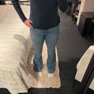 Bootcut ljusblå jeans - Säljer ett par ljusblå bootcut jeans med klassisk femficksdesign och normal passform. Jeansen har en snygg utsvängd siluett från knäet och är tillverkade i mjukt denimtyg. Perfekta för dig som gillar retrovibbar och vill ha en avslappnad look.