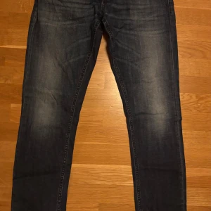 Mörkblå jeans från Dondup, storlek 34 - Snygga mörkblå jeans från Dondup, tillverkade i Italien. Modellen har klassisk femficksdesign, knapp och dragkedja i gylfen samt smal passform. Jeansen är gjorda i slitstarkt denim och har subtila slitningar för en cool look.