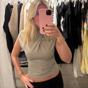 Beige omlott topp med drapering - Snygg beige topp med omlott-detalj och drapering vid halsen. Nytt skick!!