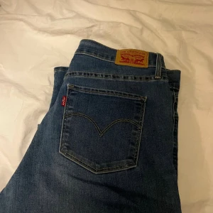 Levi's 511 blå jeans skinny fit - Säljer ett par klassiska Levi's 511 jeans i blå tvätt med skinny passform. De har fem fickor, Levi's röda tag på bakfickan och läderpatch i midjan. Jeansen är tillverkade i stretchigt denim för extra komfort och sitter snyggt längs benen.