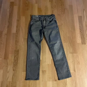 Levi's 511 grå jeans W28 L32 - Snygga grå Levi's 511 jeans i klassisk femficksmodell. Jeansen har en smal passform med raka ben och är tillverkade i mjukt denimtyg. Perfekta för dig som gillar en stilren look med lite edge. Levi's patch bak och röda loggan vid bakfickan.