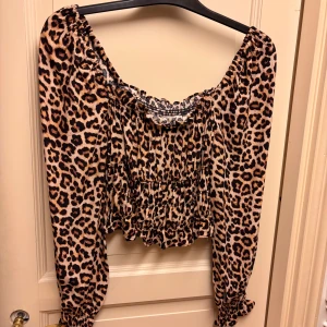 Leopardmönstrad croppad topp H&M - Säljer en croppad topp från H&M med leopardmönster. Toppen har långa puffärmar och volangkant nertill. Endast använd 1 gång!