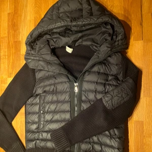 Svart Moncler Cardigan med huva - Svart catdigan från Moncler med huva. Perfekt för dig som gillar snygga kläder och vill ha något som passar till allt.