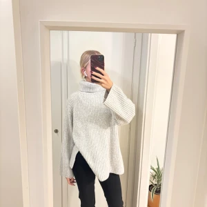 Ljusgrå stickad polotröja  - Säljer en oversized ljusgrå polotröja med ribbad struktur och breda ärmar. Tröjan har hög polokrage och slits i sidorna för en chill och modern look. Köpt på Gina tricot i strl S 