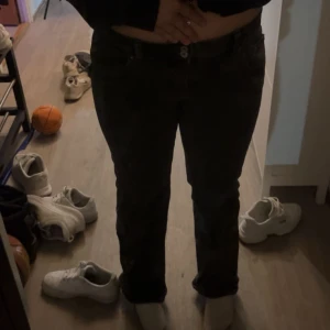Svarta raka jeans - Säljer ett par svarta jeans med rak passform och klassisk femficksdesign. Jeansen har låg midja och stängs med knapp och dragkedja. Perfekta till sneakers eller boots och funkar året runt.