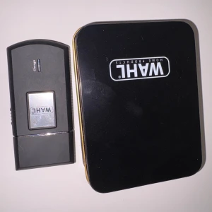 Wahl  - Kompakt och portabel Wahl reseshyvel i svart med tillhörande förvaringsbox. Laddningsbar och enkel att använda, perfekt för resor. Produkten ser ut att vara i mycket gott skick utan synligt slitage.