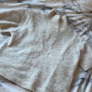 Beige polotröja från Gina Tricot - Supermjuk beige polotröja från Gina Tricot i ullblandning. Tröjan har korta ärmar, ribbad hög krage och avslut vid ärmslut och nederkant. Har använt den en gång endast❤️