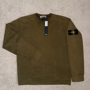 Olivgrön Stone Island sweatshirt - Säljer en olivgrön sweatshirt från Stone Island med klassisk patch på vänster ärm. Tröjan har rund hals, långa ärmar och ribbade muddar. Tillverkad i mjuk bomull, perfekt för en clean och stilren look. Nypris: 2500kr✅💯