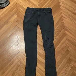 Mörk blåa Replay jeans slim fit - Snygga mörk blåa jeans från Replay med klassisk femficksdesign och diskret Replay-logga på bakfickan. Jeansen har slim passform, raka ben och är tillverkade i stretchigt bomullsmaterial för extra komfort. Perfekt för dig som gillar stilrena och moderna jeans.