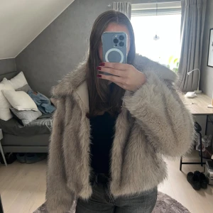 Beige pälsjacka från AMISU - Säljer en fluffig och oversized beige fejk pälsjacka från AMISU. Jackan har lång ärm, bred krage och stängs med knäppen framtill. Insidan är fodrad med glansigt tyg för extra komfort.