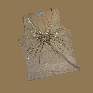 Linne med paljettdetaljer - Snyggt glittrigt guldlinne dekorerat med paljetter och pärlor i ett vackert mönster framtill. 