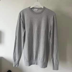 Grå kashmirer tröja - Säljer en stilren ljusgrå cashmere tröja från John Henric. Tröjan har rund halsringning och är långärmad, perfekt att bära över en skjorta. Modellen är 180cm