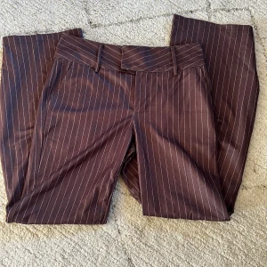 Bruna randiga kostymbyxor från Shein - Snygga bruna kostymbyxor från Shein med tunna vita ränder. Byxorna har klassisk passform, bälteshällor och raka ben. Perfekta för en stilren look och passar till många olika outfits.