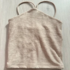 Beige ribbad linnetopp med smala band - Säljer en beige ribbad linnetopp med smala axelband och rak passform. Använd en enda gång och i topp skick