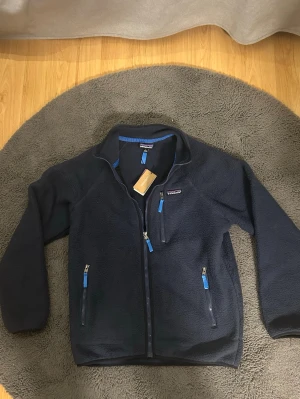 Patagonia fleece jacka  - Säljer denna sjukt snygga patagonia fleece jackan som är helt ny med tags. Storlek M och mörkblå. Hör av dig vid minsta lilla fundering! 