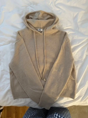 Stickad Hoodie tröja - Mjuk och bekväm stickad hoodie tröja i beige med fin guld detalj. Perfekt får både vinter och sommar om man behöver en tröja :)