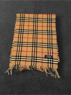 Rutig beige ullhalsduk från Burberry - Klassisk beige halsduk från Burberry i 100% lammull med ikoniskt rutigt mönster i svart, vitt och rött. Halsduken har fransar i ändarna och en snygg Burberry-label. Perfekt accessoar för att lyfta din outfit.