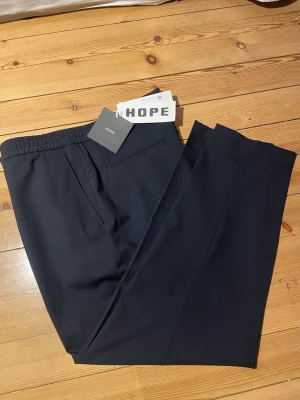HOPE byxor - Helt oanvända HOPE work dash trousers i färgen navy. Storlek m52/w44 (sitter som L). Nypris 1800