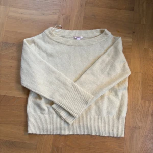 Oversized offshoulder stickad tröja - Mysig offshoulder stickad tröja i ljusbeige med bred ribbad kant vid ärmslut och nederkant. Tröjan har en avslappnad passform och är perfekt för dig som gillar en enkel men trendig look. Passar till både jeans och kjol.