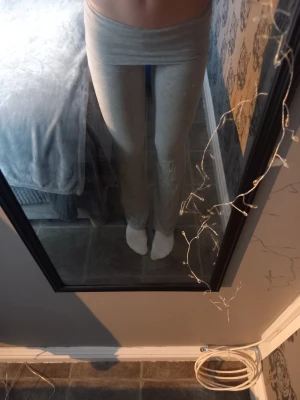 Gråa mjukisbyxor med hög midja - Säljer ett par ljusgrå mjukisbyxor med bred, hög midja och tight passform. Byxorna är raka i benen och gjorda i mjukt bomullsmaterial, perfekta för chill dagar hemma eller när du vill vara bekväm men ändå se snygg ut.