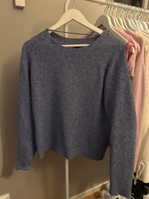 Blå stickad tröja  - Mysig blå stickad tröja med rund halsringning och långa ärmar. Tröjan har en enkel och stilren design, perfekt att slänga på sig när det är kyligt. Passformen är normal och materialet känns mjukt mot huden.