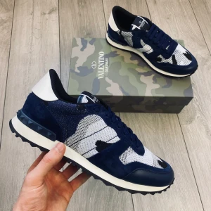 Valentino Garavani Rockrunner sneakers - Snygga Valentino Garavani Rockrunner sneakers i marinblått, vitt och svart med coolt camouflage-mönster. Skorna har detaljer i mocka och skinn, samt klassiska nitar på hälen. Perfekta för dig som vill sticka ut med exklusiva och trendiga sneakers. Skriv vilken storlek ni har om ni är intresserade 