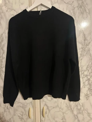 Svart stickad tröja från Pull&Bear - En klassisk svart stickad tröja från Pull&Bear i storlek S. Tröjan har rund halsringning, ribbade muddar och lång ärm. Perfekt basplagg till garderoben och enkel att matcha med allt.